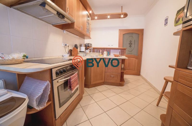 A kitchen in a 3-room apartment with wooden cabinets and ceramic flooring.
