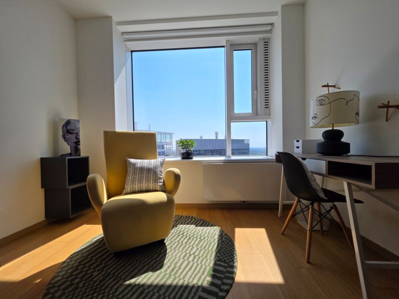 Stylish armchair, writing desk, and wooden decor flooring in a studio apartment.