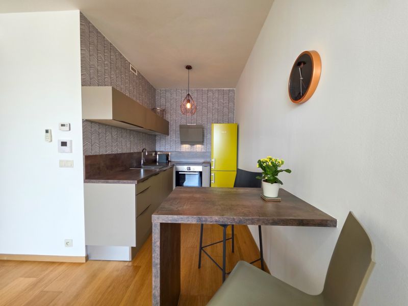A kitchen in a studio apartment with a yellow refrigerator and wallpapered walls.