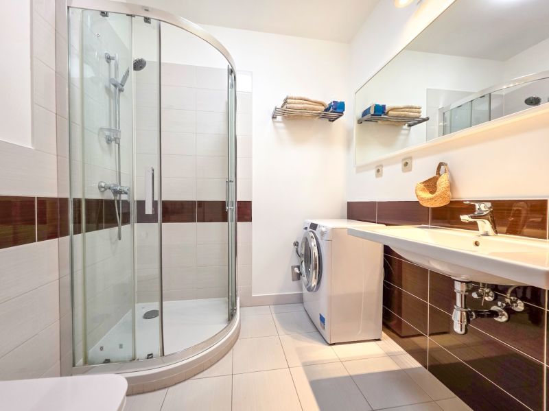 Beautiful bathroom in a studio apartment with a shower and a washing machine.