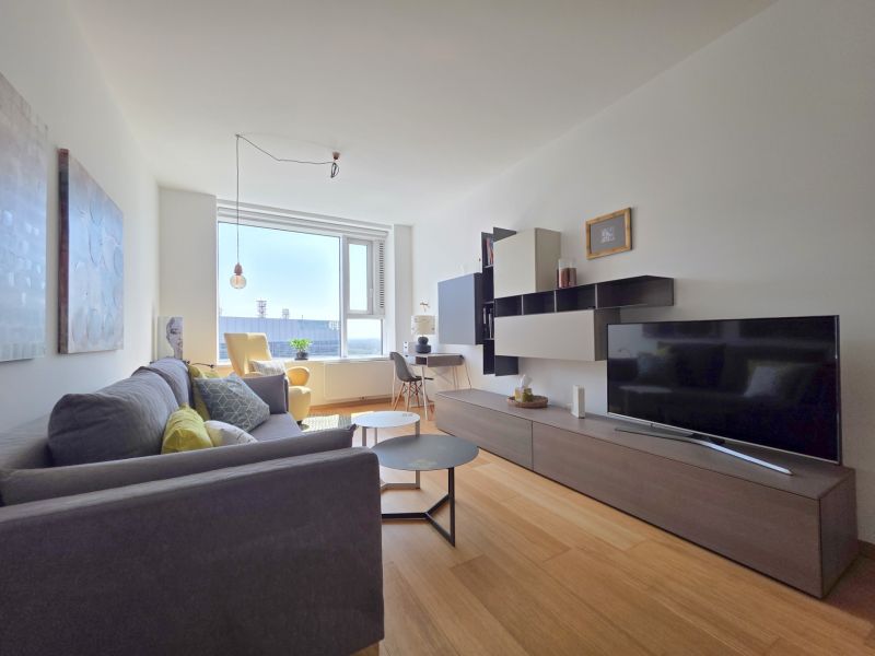 Living room in a studio apartment with wood-patterned flooring and comfortable seating.