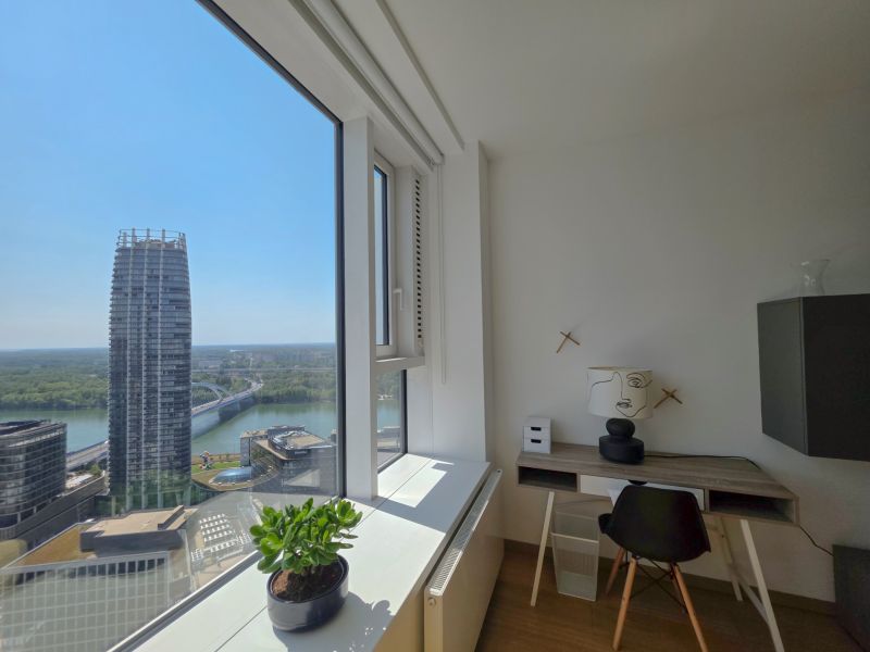 Interior of a 1-bedroom apartment with a view of the river and modern architecture.