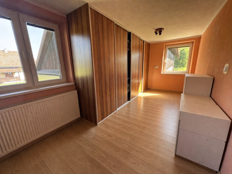 A room in a family house with a wooden decor floor and a built-in wardrobe.
