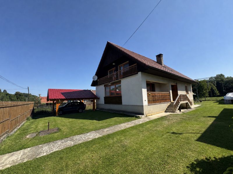 A family house in Liptovské Kľačany with a lawn and a carport.