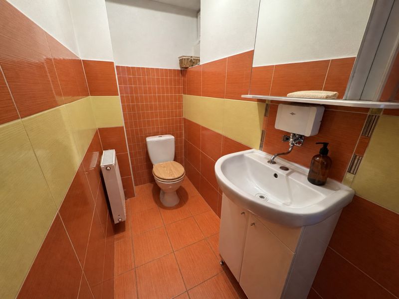 A bathroom with tiles and a sink in a family house with orange and yellow tiles.