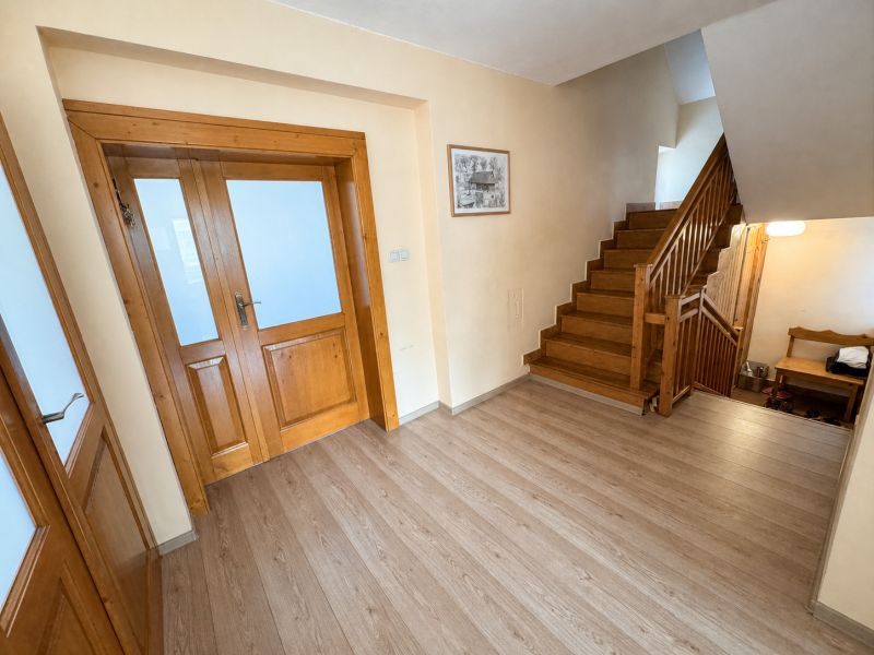 Interior of a family house with a staircase, wooden doors, and a floor with a wooden decor.