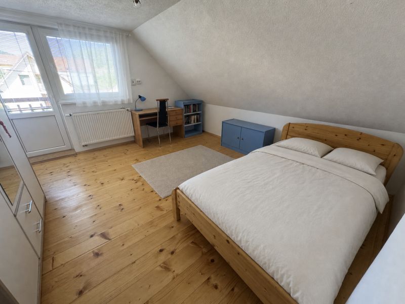 Attic room in a family house with a wooden decor floor and a desk.