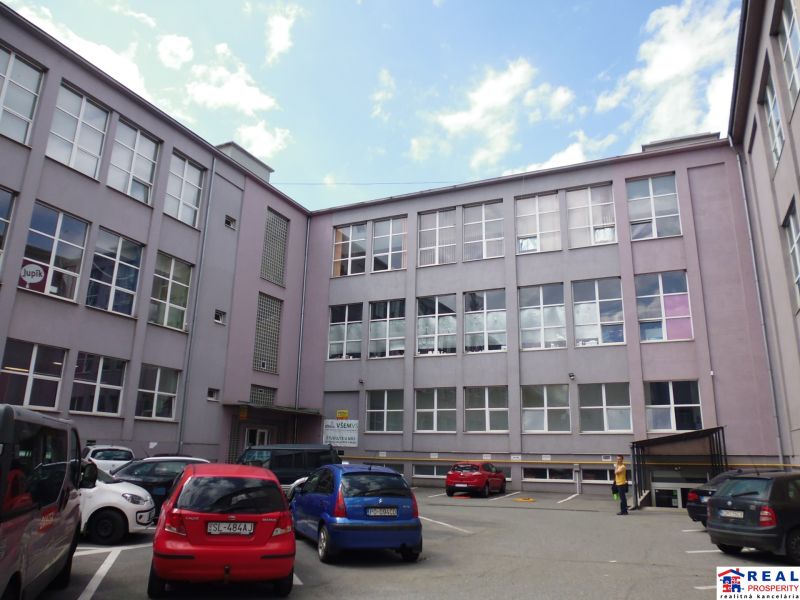 An office building on Masaryk Street in Prešov, in front of which cars are parked.