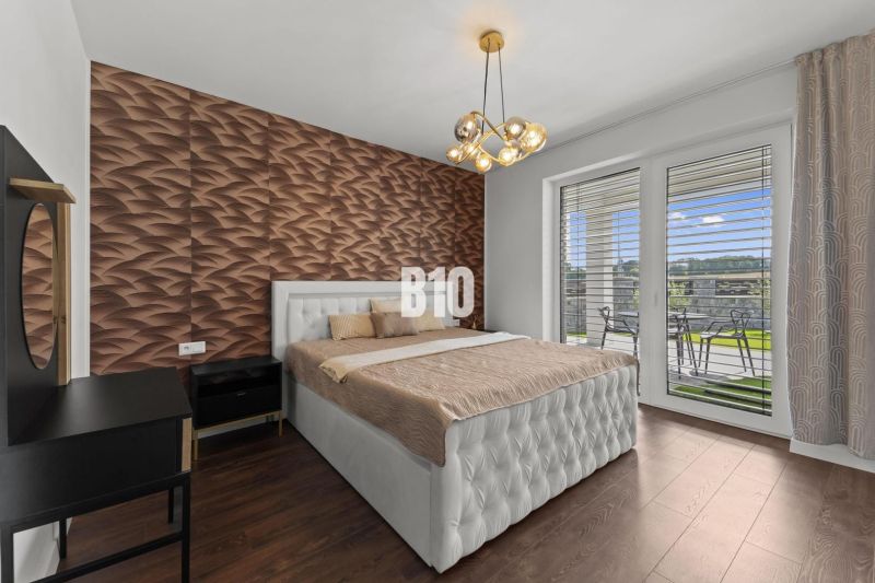 A bedroom with wood-patterned flooring, a quilted headboard, and a view of the terrace.
