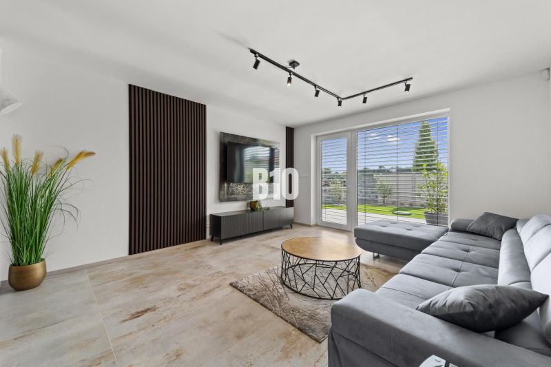 Living room in a family house with a sofa, television, and a window with a view.