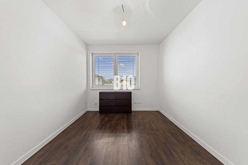 A room in a family house with a window, a dresser, and a floor with a wooden decor.