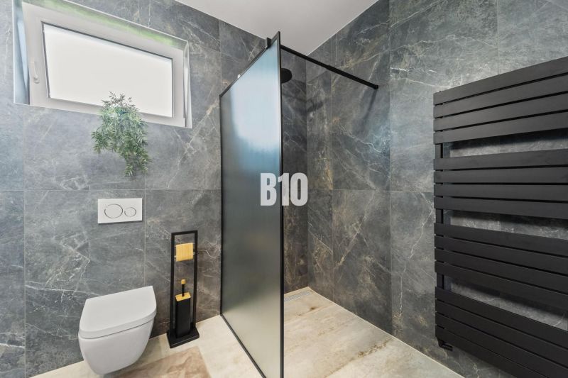 A bathroom in a family house with a black radiator and a shower enclosure.