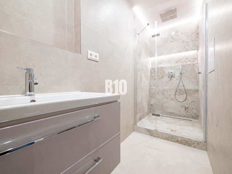 A bathroom in a 3-room apartment with a modern shower and sink.