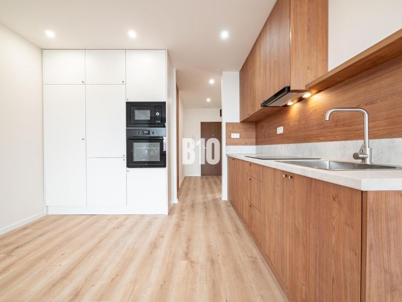 A kitchen in a 3-room apartment with white cabinets and a wood-patterned floor.