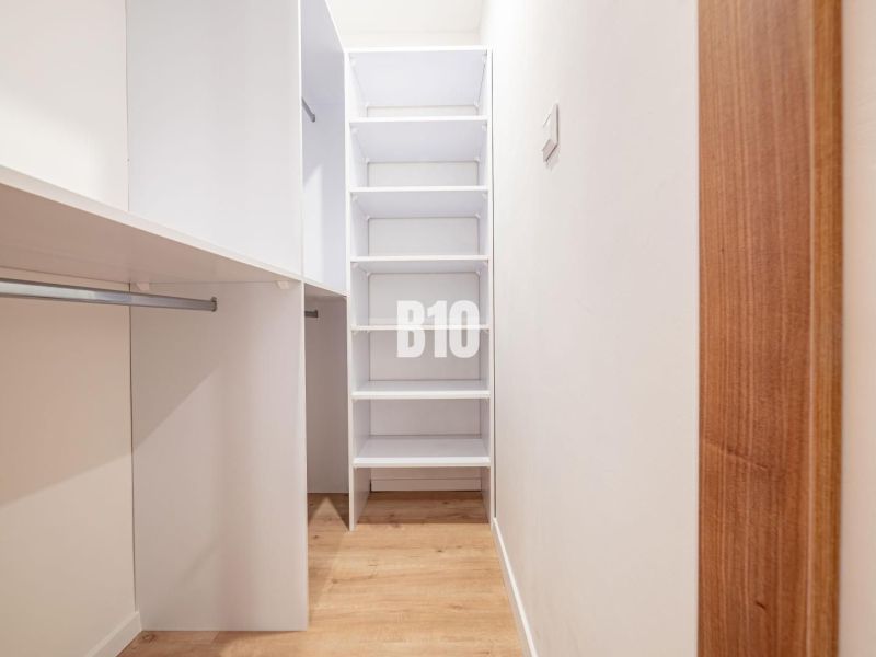 A wardrobe in a 3-room apartment with shelves and a wooden decor floor.