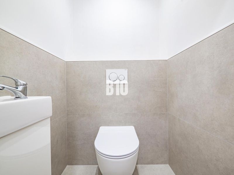 Bathroom in a 3-room apartment with toilet and sink, simple tiles on the walls.