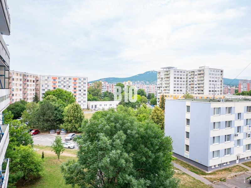 View from a 3-room apartment in Nitra of panel buildings and a parking lot with cars.