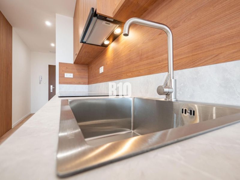 Modern kitchen in a 3-room apartment with a stainless steel sink and wooden decor.