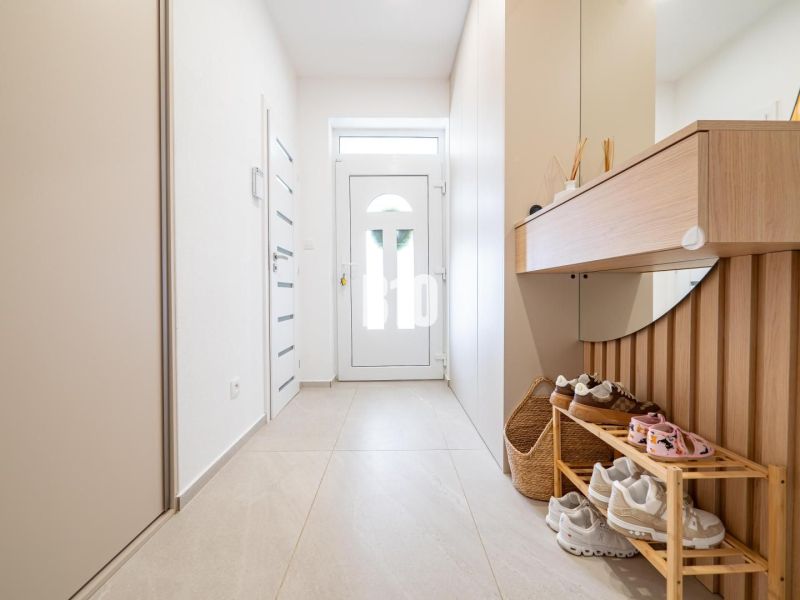 Interior of a family house with a bright hallway, shoe cabinet, and mirror.