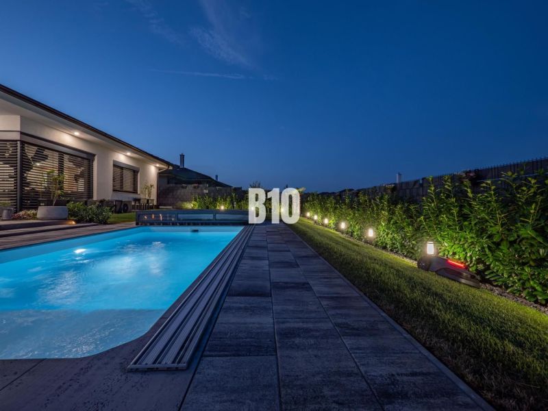 A night garden at a family house in Nitra with a lit-up pool and terrace.