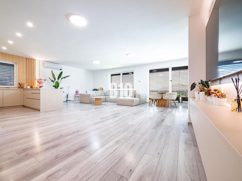 Spacious living room with wood-decor flooring and large seating area in a family house.