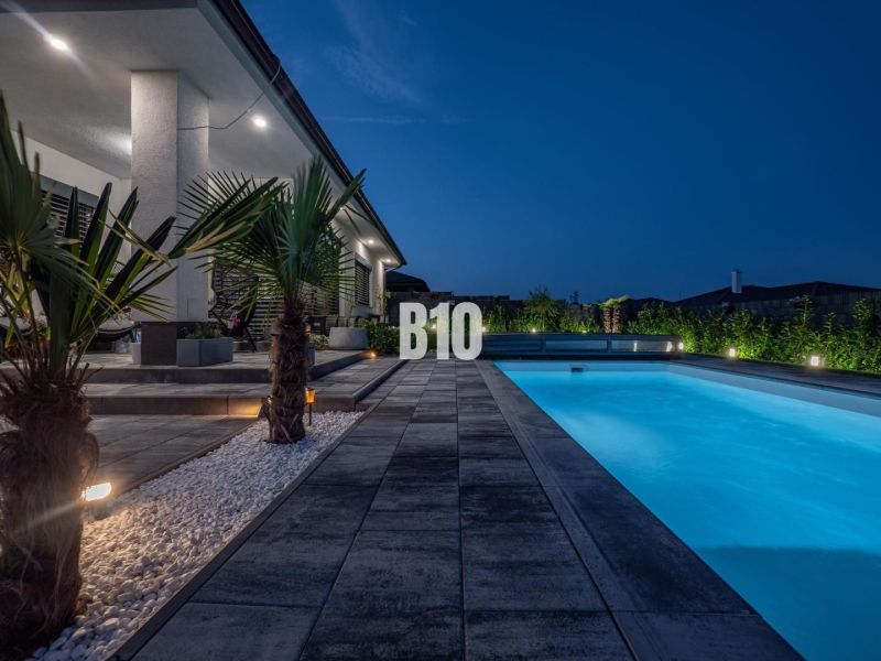 A family house in Nitra with a swimming pool and an illuminated garden in the evening.