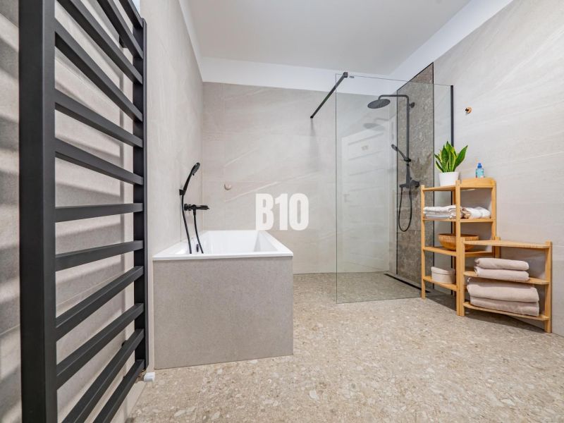 A bathroom in a family house with a bathtub, a shower corner, and a towel rack.