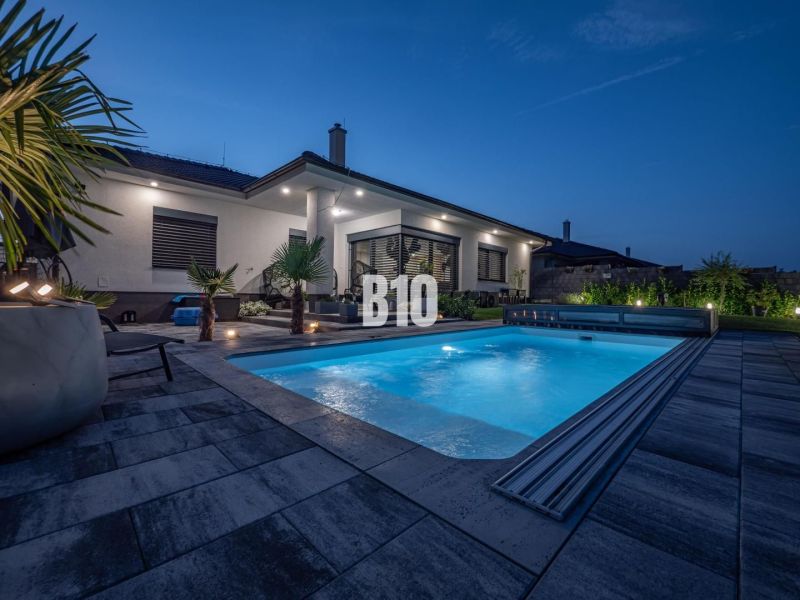 A family house in Nitra with a swimming pool and garden seating in an evening atmosphere.