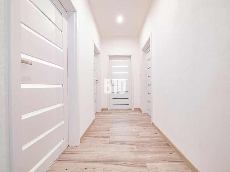 A bright hallway in a family house with a wooden decor floor and white doors.