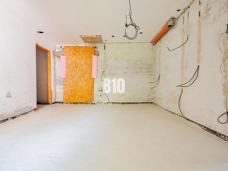 An unfinished room with bare walls and hanging cables in a family house.