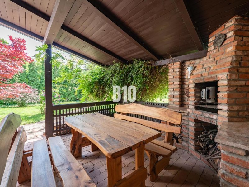 Terrace of a family house in Nitra with wooden seating, a grill, and greenery in the surroundings.