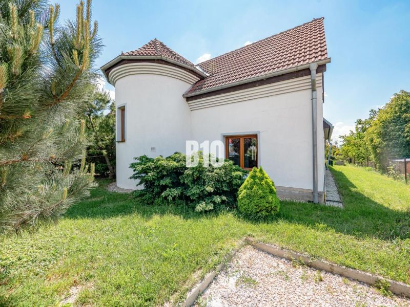 A family house in Nitra with windows, a garden, and a sloped roof in a green area.