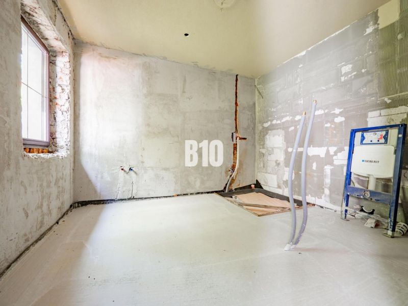 Partially reconstructed room in a family house with unfinished installations and bare walls.