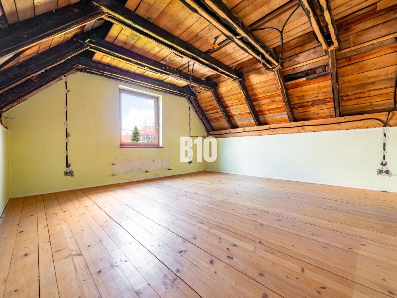 The attic of a family house with a wooden decor floor and roof beams.