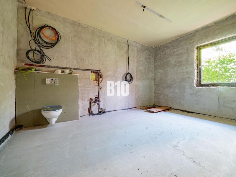A construction space with a toilet installation and a window in a family house.