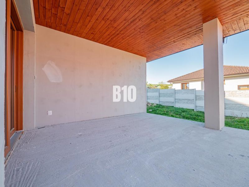 The terrace of a family house in Nitra with a wooden ceiling and an adjacent concrete fence.