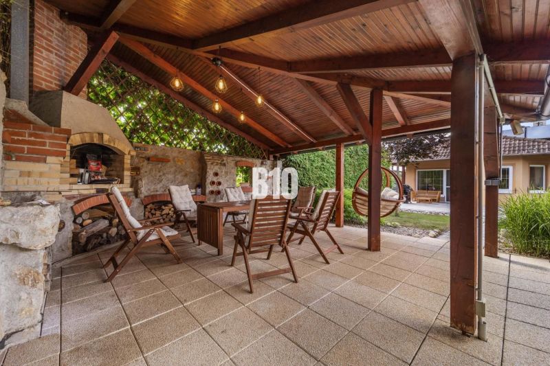 A covered terrace with a fireplace and wooden chairs at a family house in Nitra.