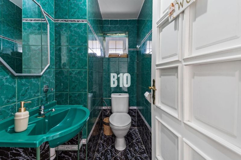 A bathroom in a family house with green tiles and a sink.