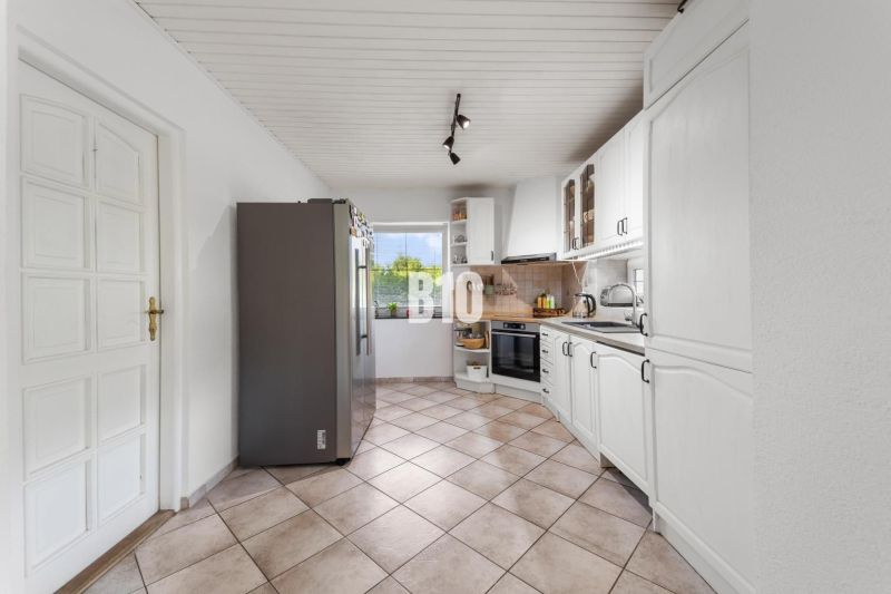 A kitchen with white cabinets and appliances in a family house.