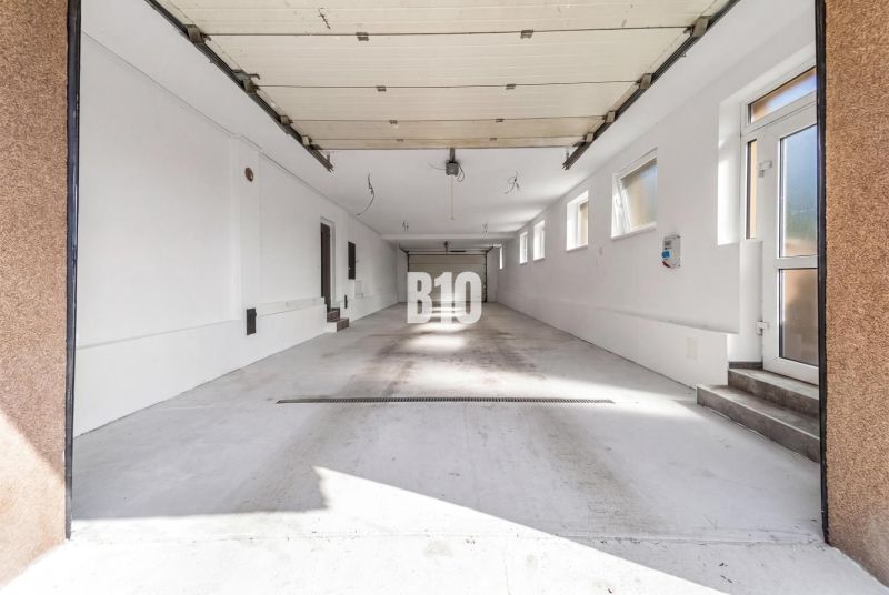 A spacious garage in a family house in the city of Nitra with several windows and white walls.