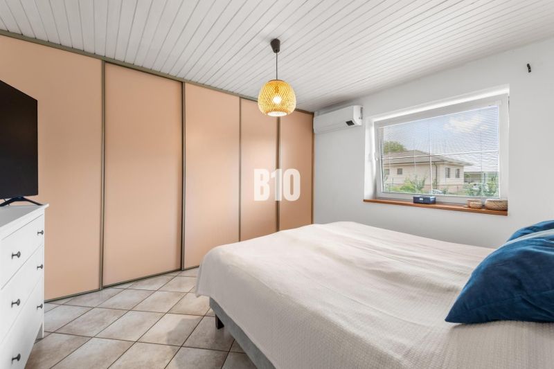 Bedroom in a family house with a large built-in wardrobe, air conditioning, and a window.