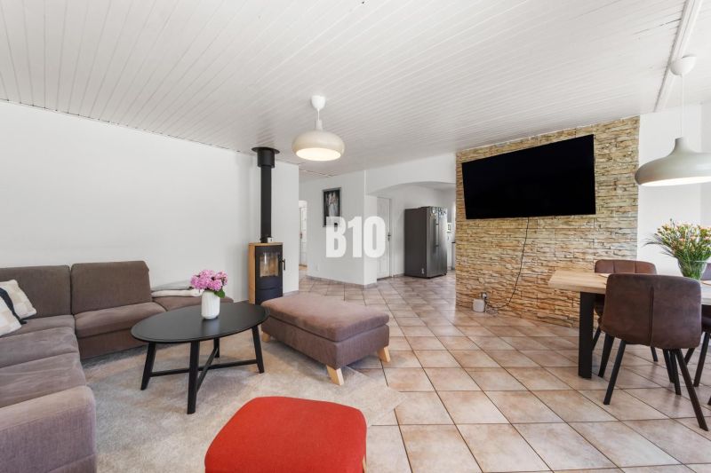 Living room in a family house with a fireplace and a television on a stone-clad wall.