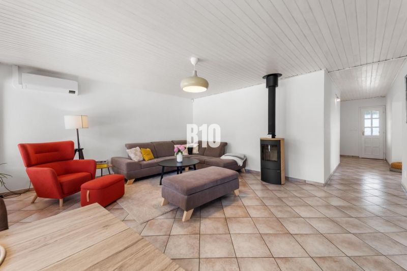 Living room in a family house with a fireplace, a red armchair, and a gray sofa.