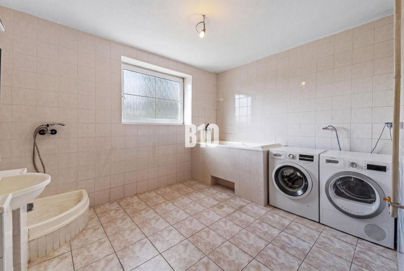 A bathroom in a family house with a washing machine, bathtub, and shower.