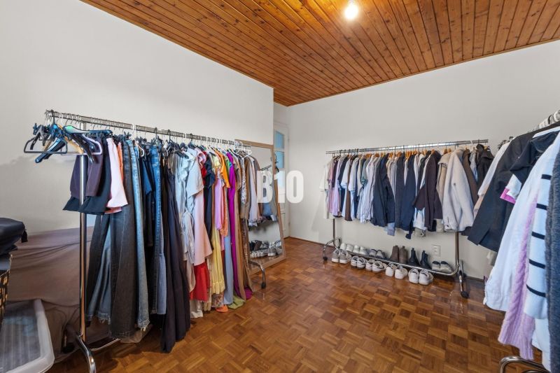 A wardrobe in a family house with hanging rods and a wooden decor floor.