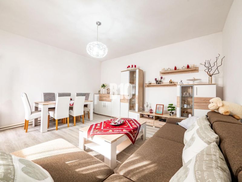 Living room with a dining table, wood-patterned floor, and a brown sofa in a family house.
