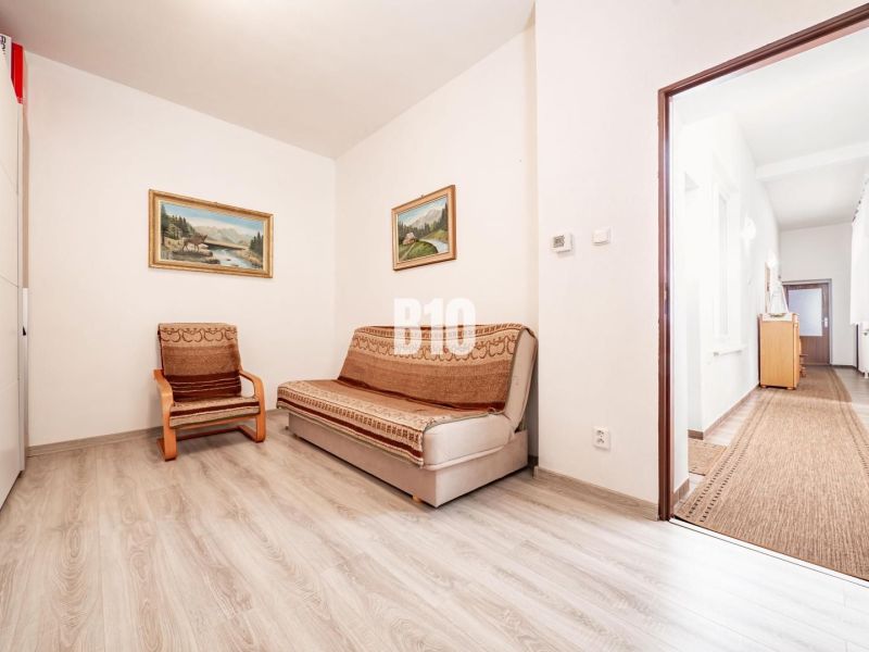 A room in a family house with a sofa, an armchair, and a wooden decor floor.