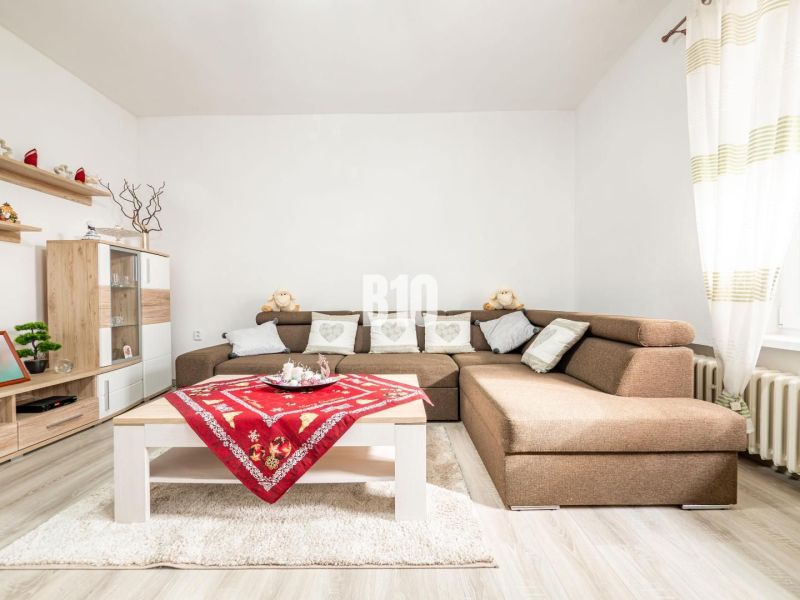 Living room in a family house with a corner sofa, wooden decor, and colorful placemats.