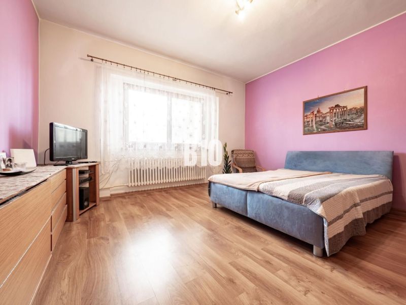 Bedroom in a family house with wood-decorated flooring, furniture, and a television.