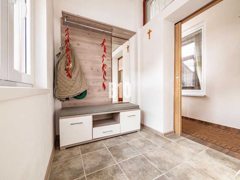 Entrance hall in a family house with a coat rack, seating, and tiled floor.